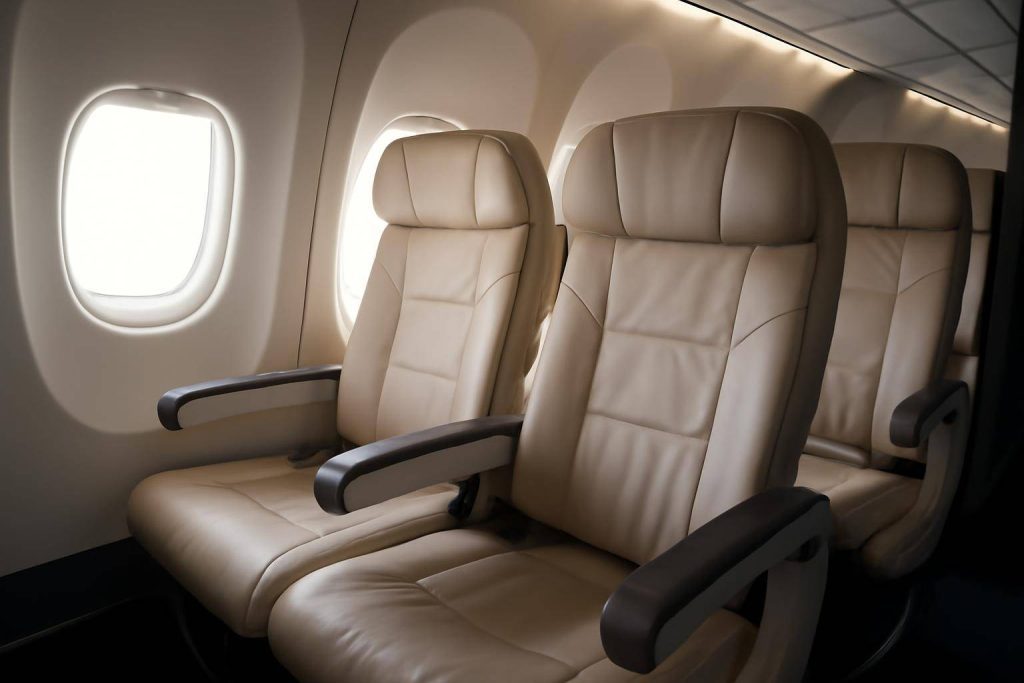 Three empty beige leather airplane seats beside windows in a well-lit aircraft cabin. The seats have armrests, and daylight shines through the windows, creating a calm and clean atmosphere.